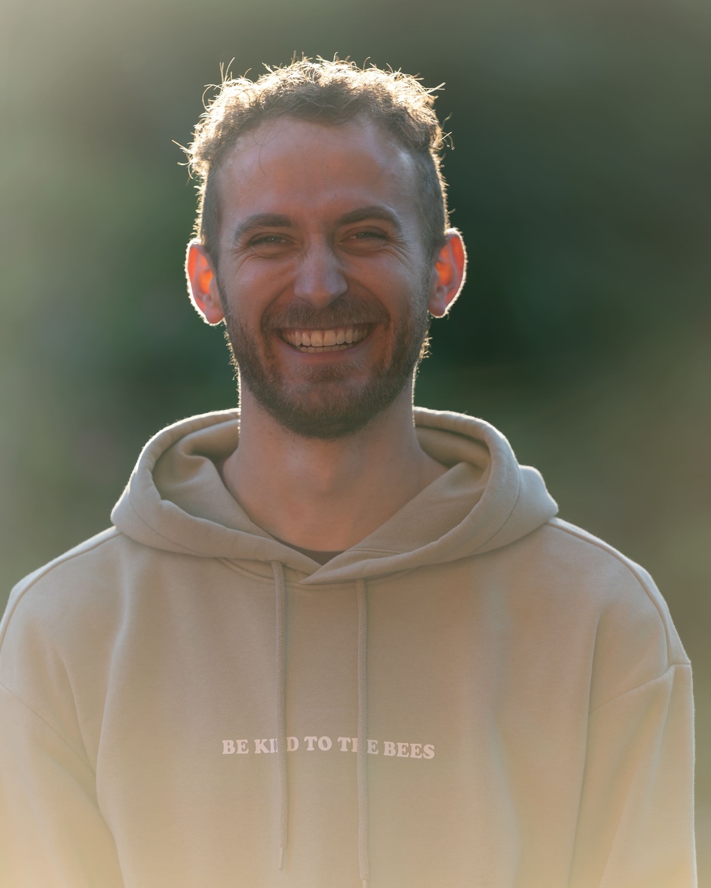 Junger Mann mit braunen Haaren und beigem Kapuzenpullover